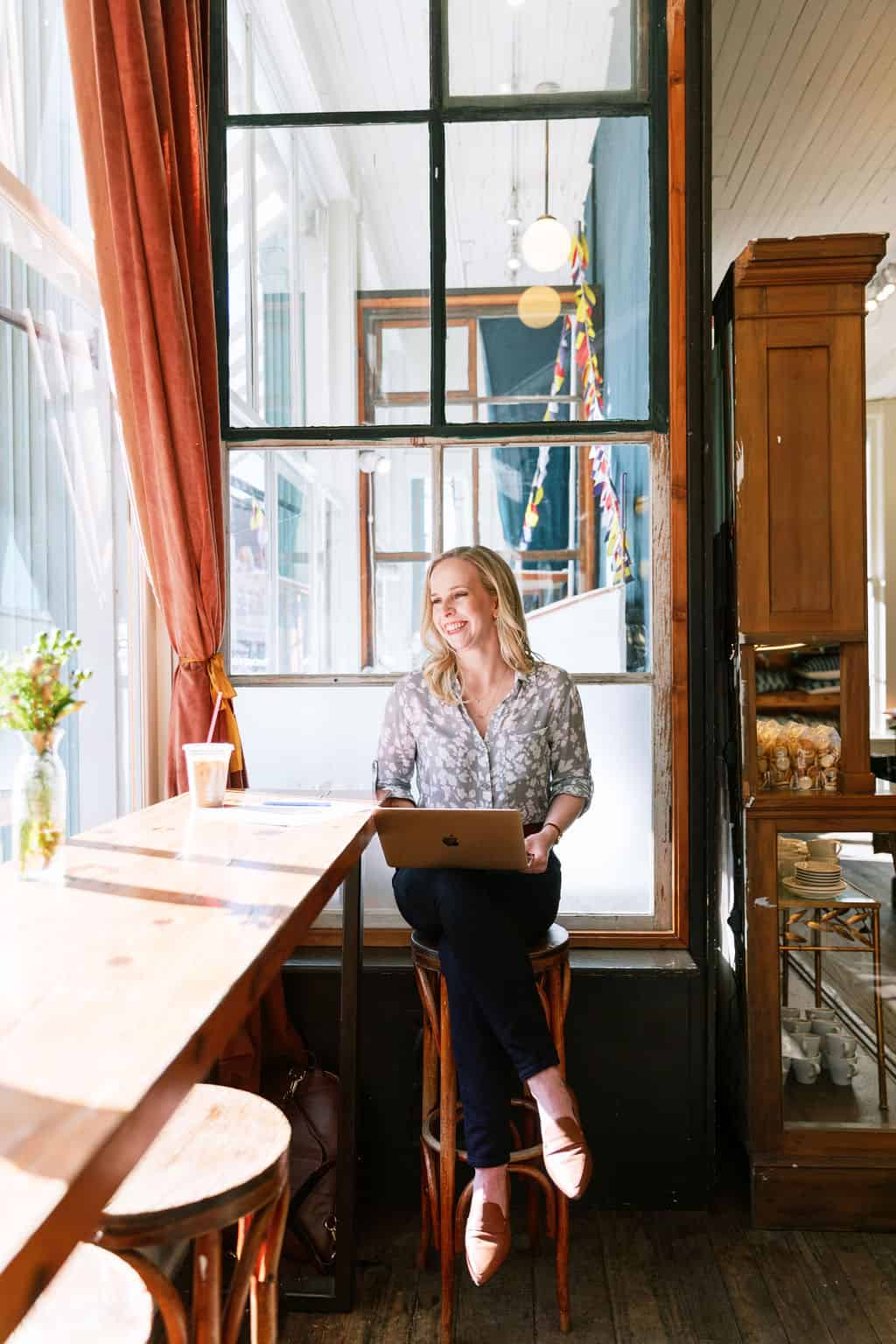 Showit website designer, Sarah Blodgett of Digital Grace Design, sits in an elegant coffee shop on her laptop