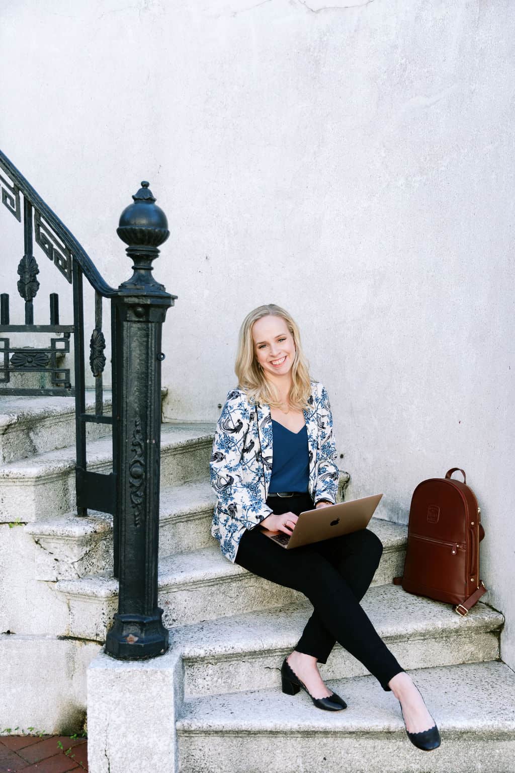 Digital Grace Design founder, Sarah Blodgett, sits on some steps with her laptop
